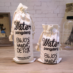 Two white drawstring bags with black text on a wooden surface.
