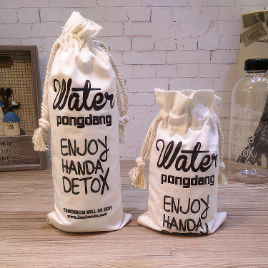 Two white drawstring bags with black text on a wooden surface.